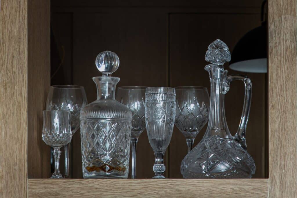 A traditional wine glass pitcher and wine glasses in a wooden cabinet