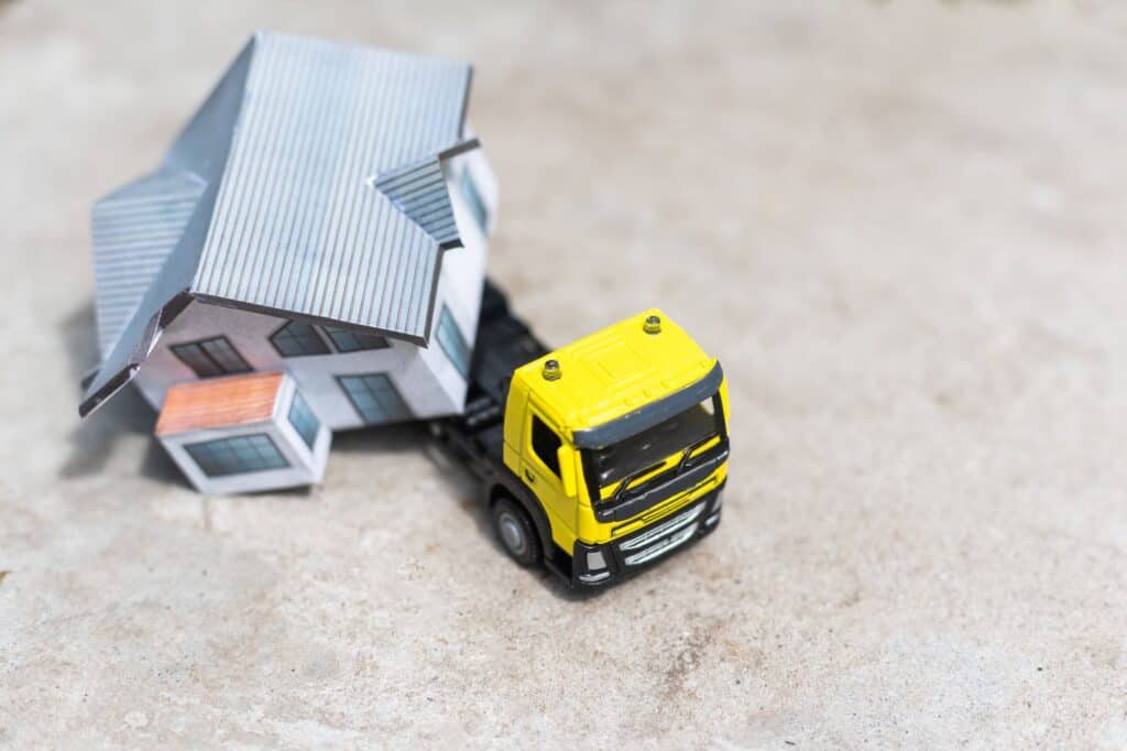 A yellow toy truck carrying a house