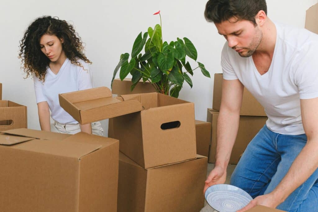 A couple packing cartons for their move in the concept of reasons for moving to Islington.