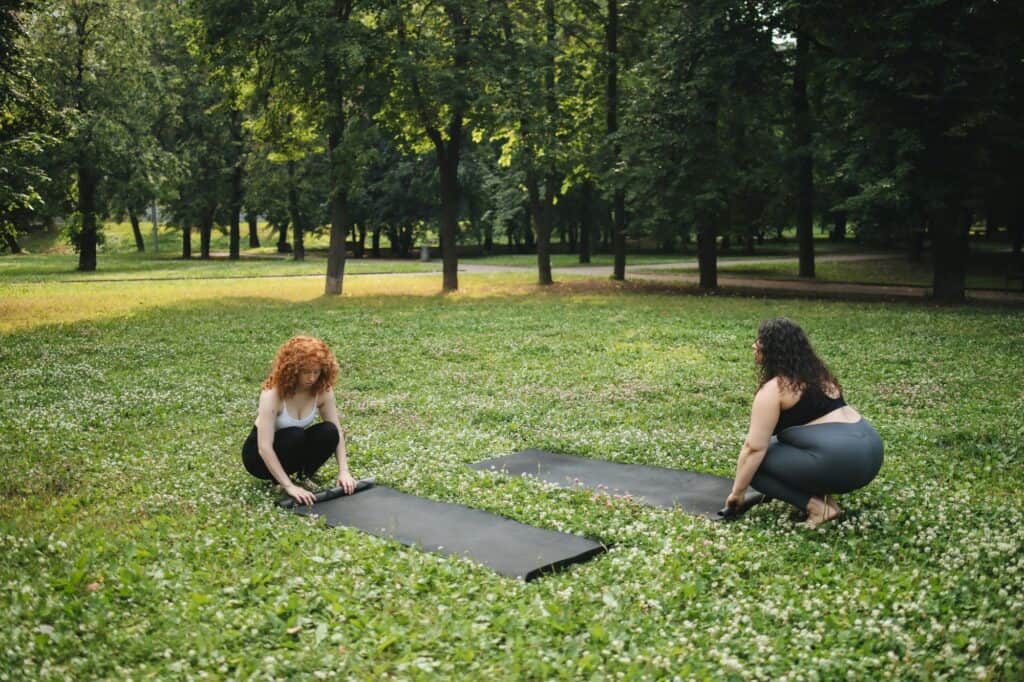 Friends placing yoga mats on the lawn