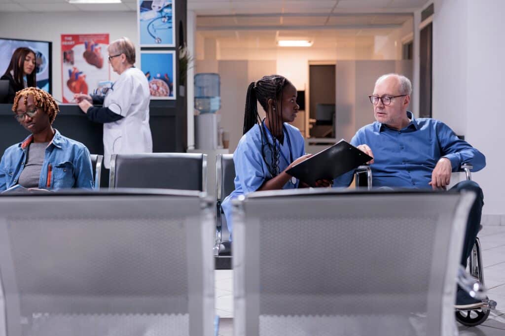 A nurse speaking with a senior patient while a doctor and a nurse talking in the background and another patient waiting for her turn in a healthcare facility in the concept of 'top services and amenities in Islington'.