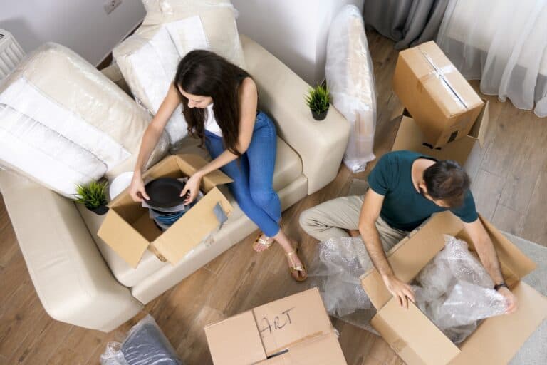 High-angle shot of a couple unpacking items in the living room in the concept of 'Islington removals cost'.